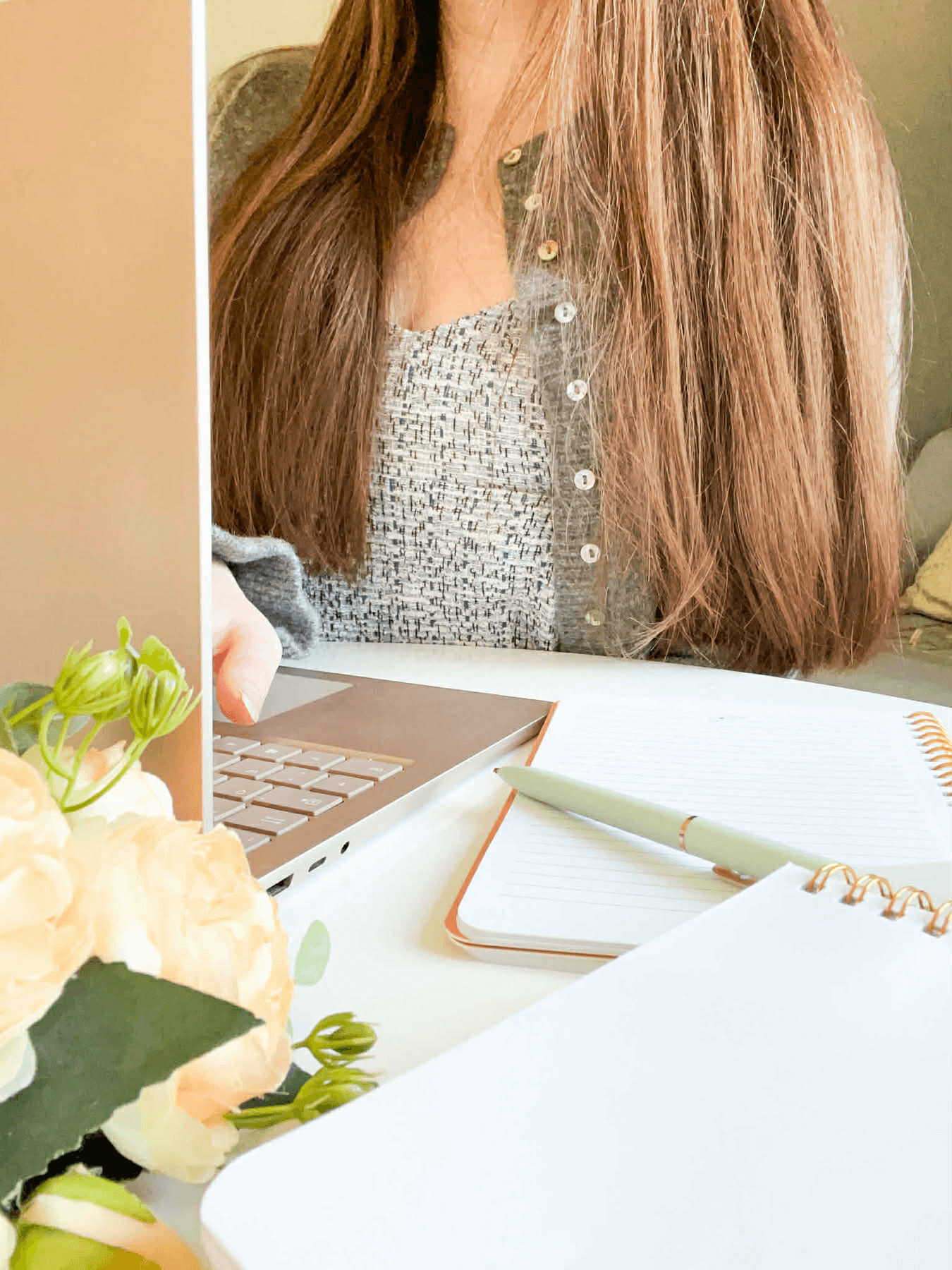 Une rédactrice web SEO freelance en train de rédiger sur son ordinateur et ses carnets